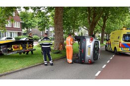 Auto belandt op zijn kant na aanrijding met boom