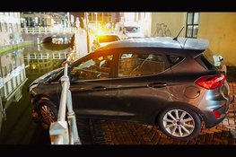 Auto hangt boven gracht na botsing in Alkmaar: bestuurder aangehouden voor rijden onder invloed