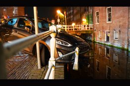 Auto hangt boven gracht na botsing in Alkmaar: bestuurder aangehouden voor rijden onder invloed